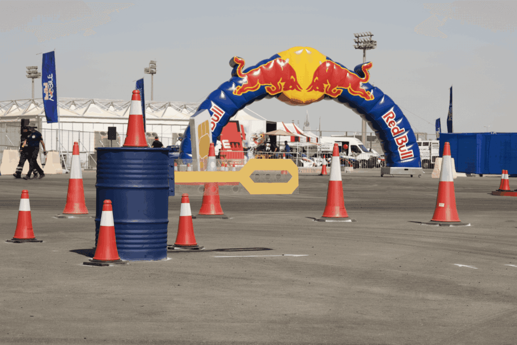 A Red Bull event scene featuring traffic cones, a blue barrel, and an inflatable arch, showcasing image.