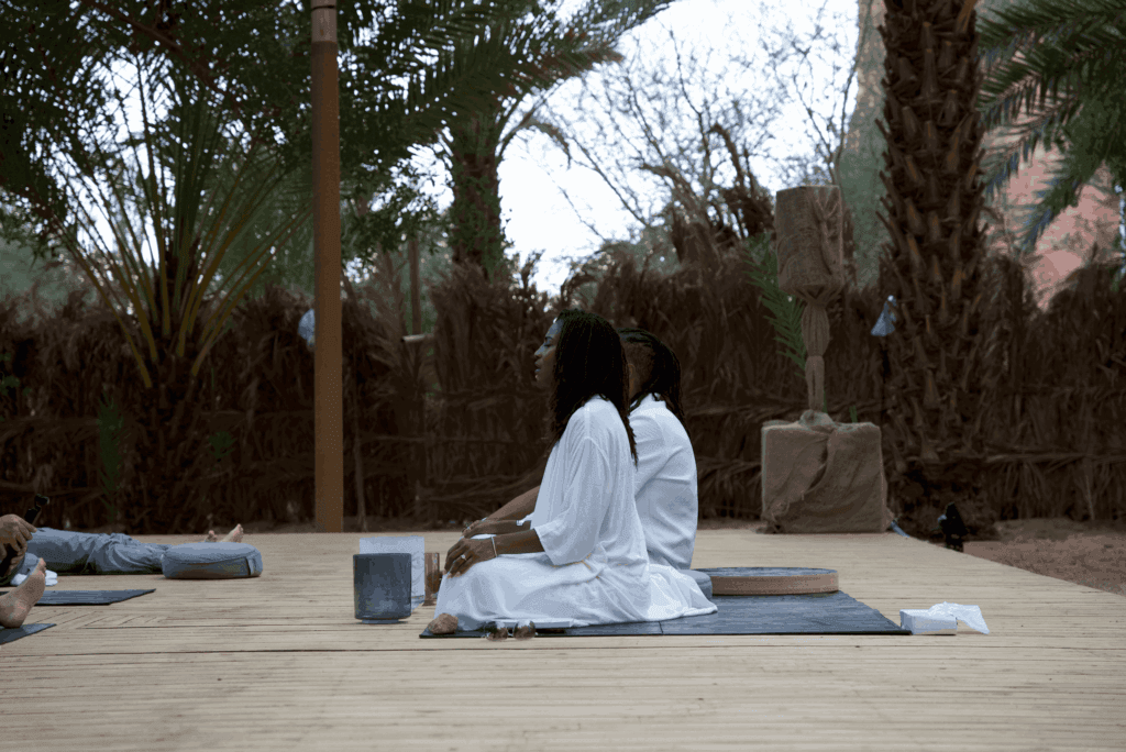 A meditation session in an outdoor setting with participants in white robes, highlighting image.