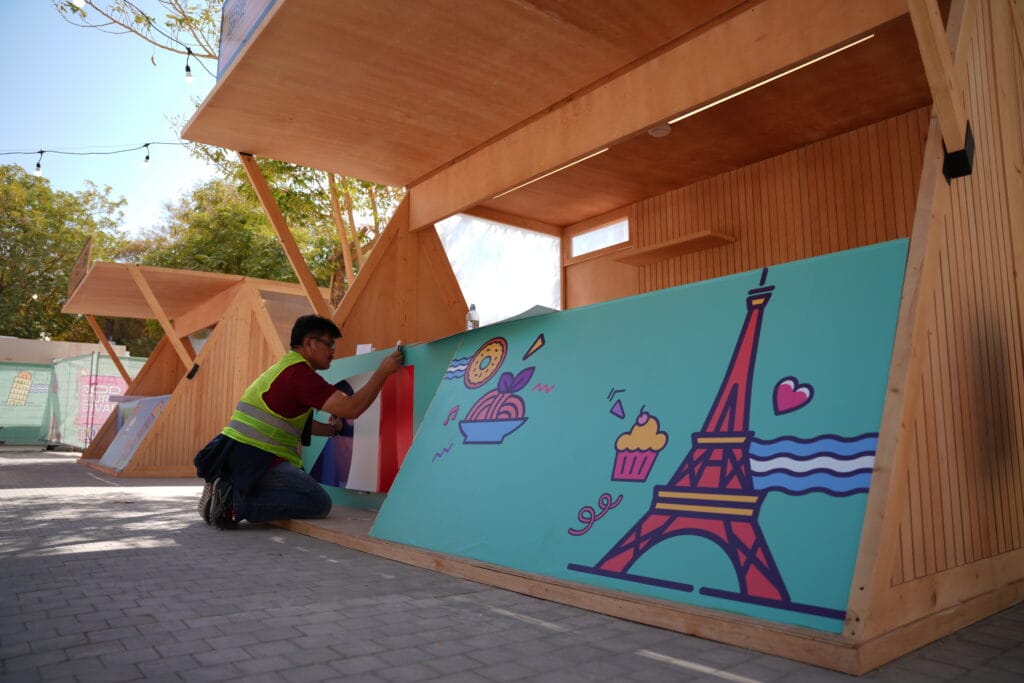 Man installing Parisian food stall art.