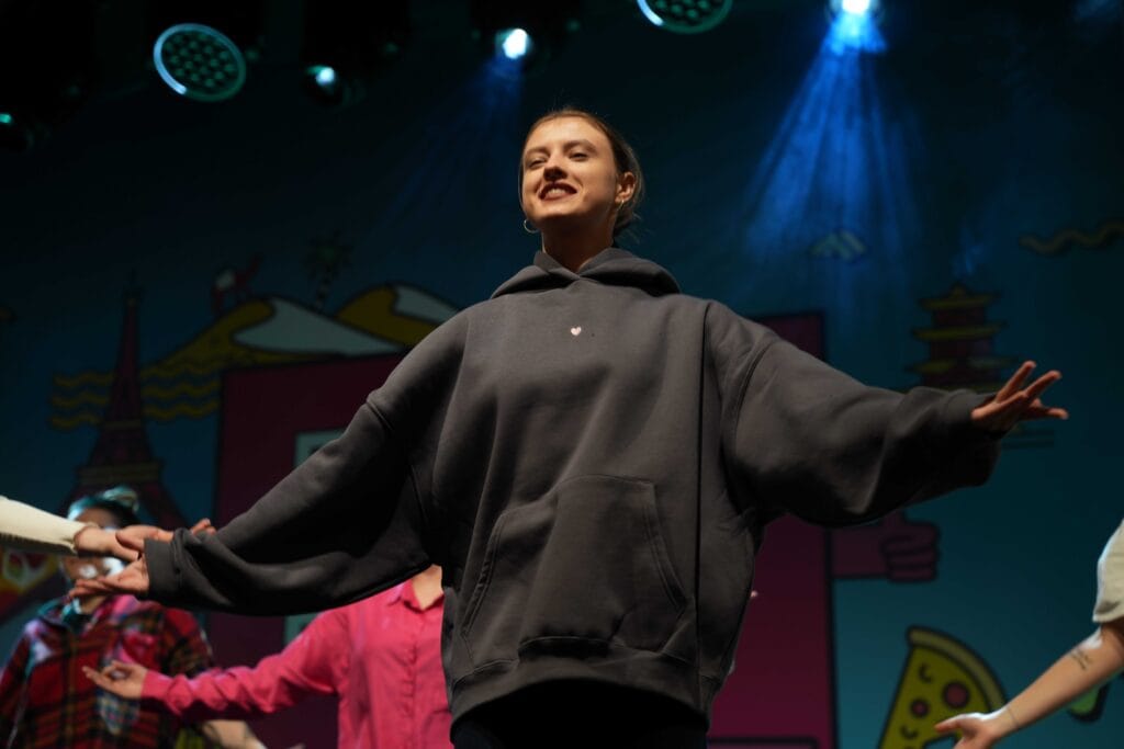 Woman in grey hoodie onstage.