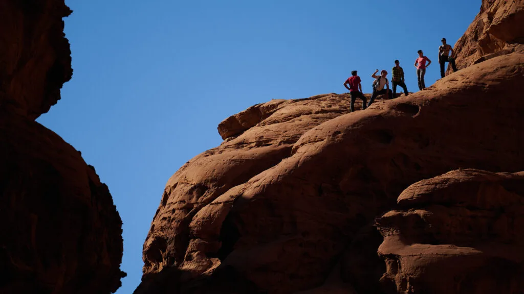 Hikers atop red rock formation.