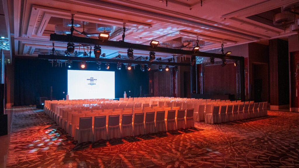 An event hall with rows of white chairs and dramatic lighting, showcasing the image.