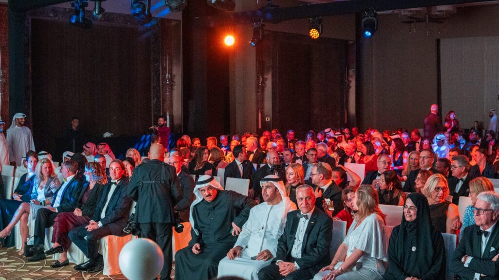 A diverse audience gathered at an event, showcasing various attire and expressions, highlighting image.