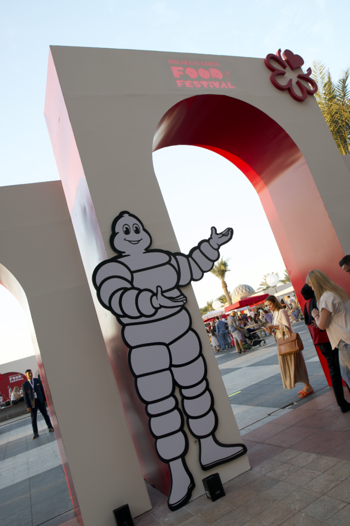 Entrance to the Michelin Guide Food Festival featuring a cartoon Michelin Man welcoming guests, showcasing image.
