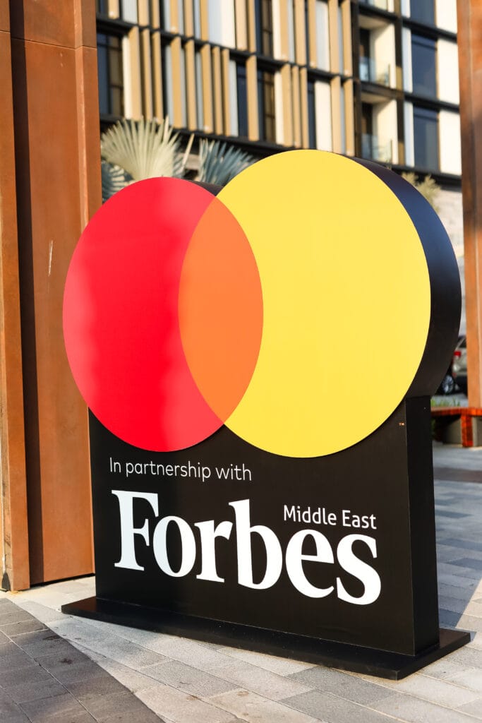 A partnership sign featuring the Forbes logo and colorful circles, showcasing image.
