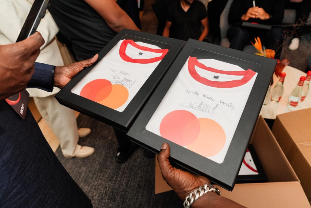 Two framed t-shirts with red collars and signatures, showcasing image.