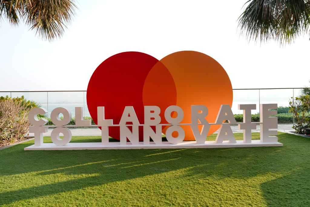 A vibrant display featuring the words 'Collaborate to Innovate' with red and orange circles in a lush outdoor setting, showcasing image.